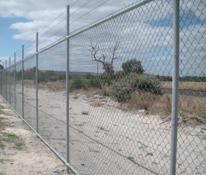 Galvanised chain wire fence installed along a rural property boundary with open land and vegetation