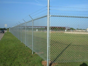 Galvanised chain wire security fence with angled extensions installed along a roadside perimeter