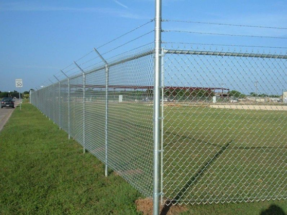 Galvanised chain wire security fence with angled extensions installed along a roadside perimeter