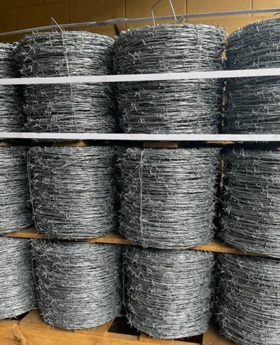 Stacked rolls of galvanized barbed wire used for perimeter security and fencing applications